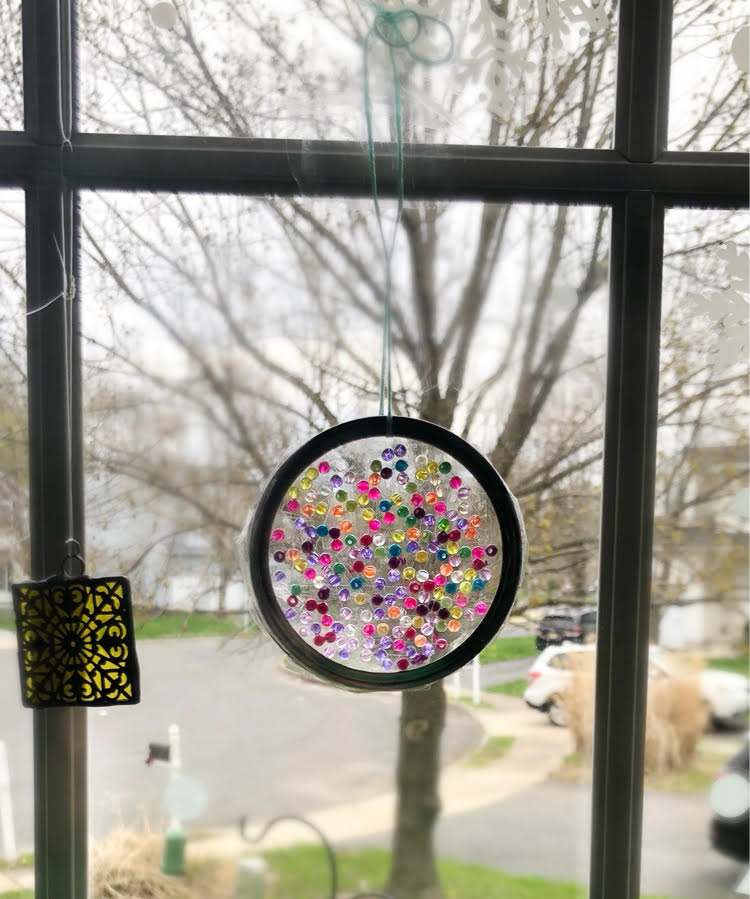 a beautiful suncatcher made with a mason jar ring, iridescent beads and Duck tape.