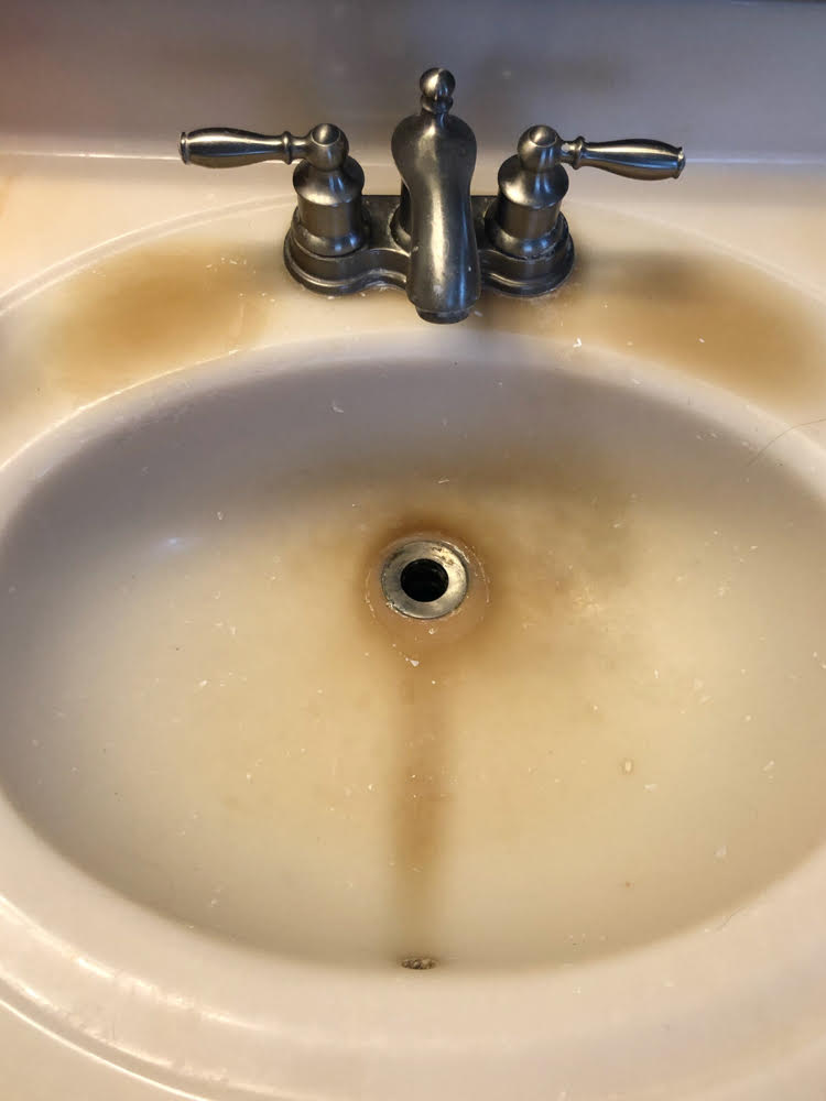 a cultured yellowed marbled sink badly in need of refinishing