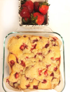 fresh strawberry coffee cake and a ceramic container filled with strawberries