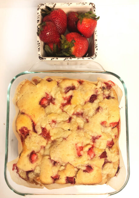 fresh strawberry coffee cake and a ceramic container filled with strawberries