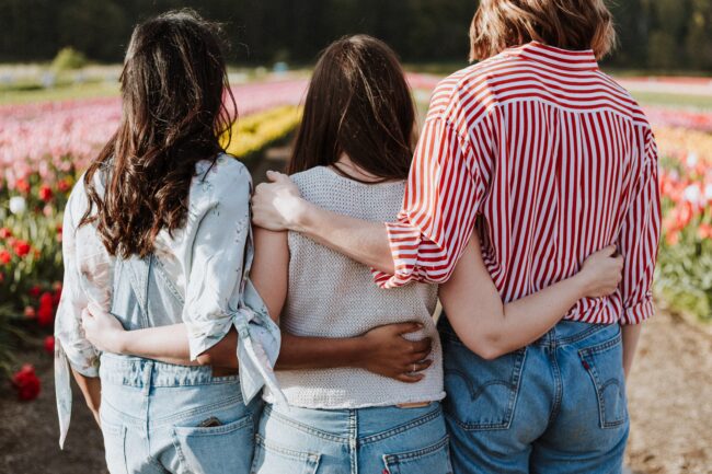 girls hugging in a field of flowers