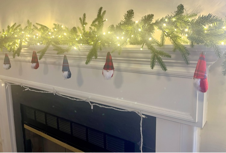 Fireplace decorated with a faux pine garland with lights.