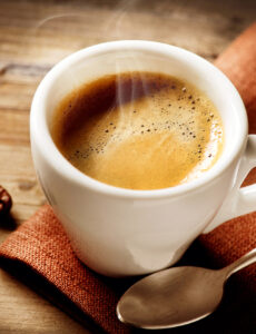 A steaming cup of coffee on a wood table