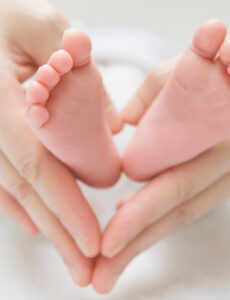 baby feet in the hands of a parent making a heart sign