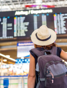 a woman looking at a flight arrivals and departures board