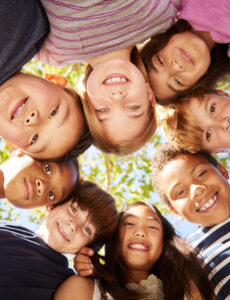 a diverse circle of happy kids looking down at the camera