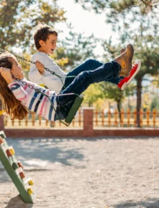 children enjoying an outdoor playground swing set