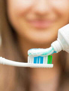 woman putting toothpaste on toothbrush