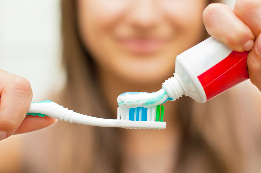 woman putting toothpaste on toothbrush