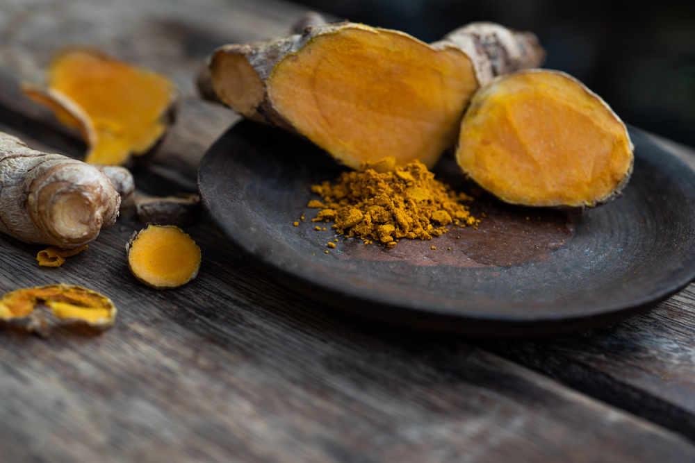 Turmeric Powder and Roots on Wooden Table