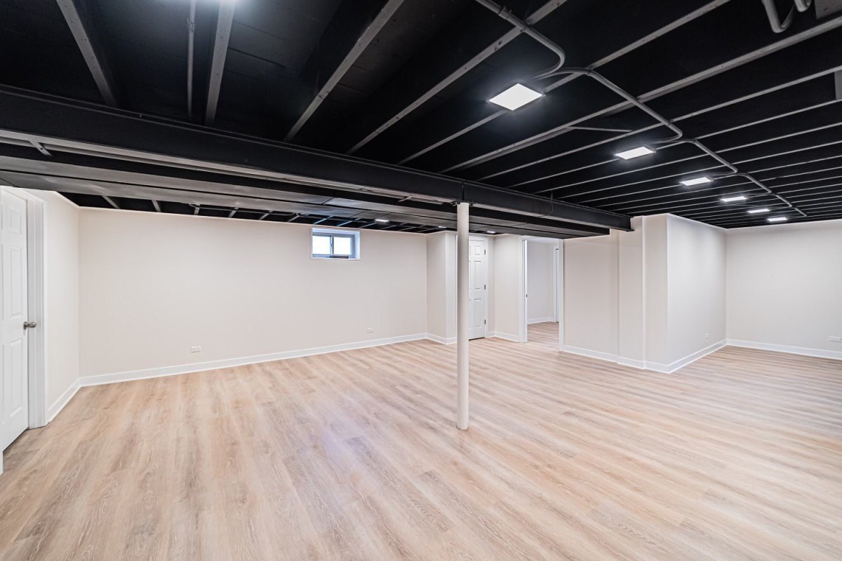 finished basement with black painted ceiling and light oak vinyl flooring