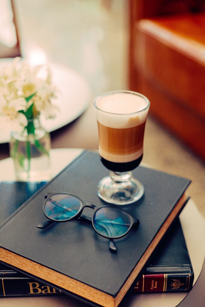 a coffee table with a hot drink, books and reading glasses.