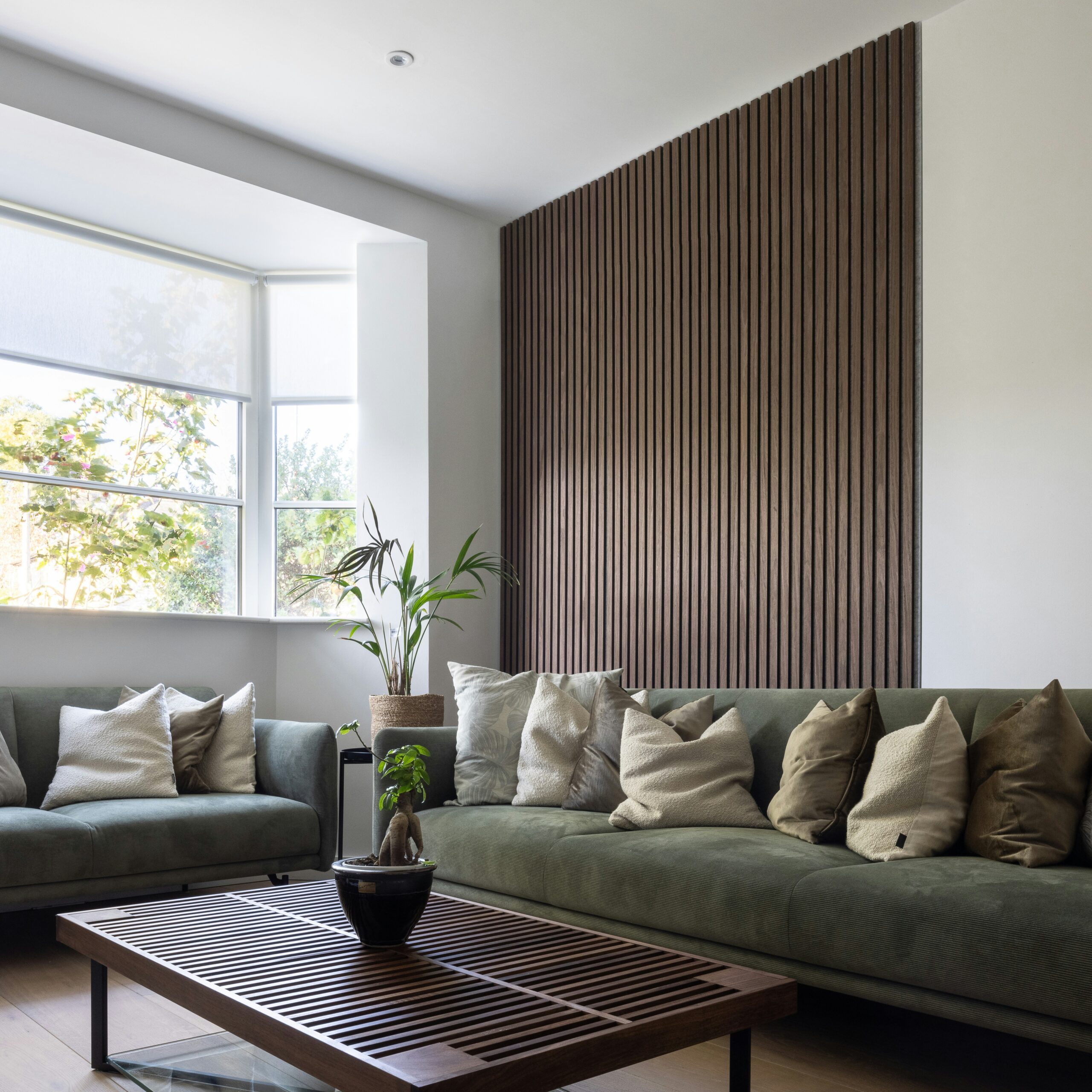 living room with wood slat wall and moss green sofa